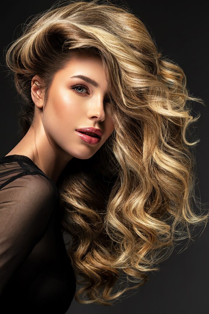 Portrait of a  beautiful woman with a long hair. Pretty blonde girl with curly hairstyle.