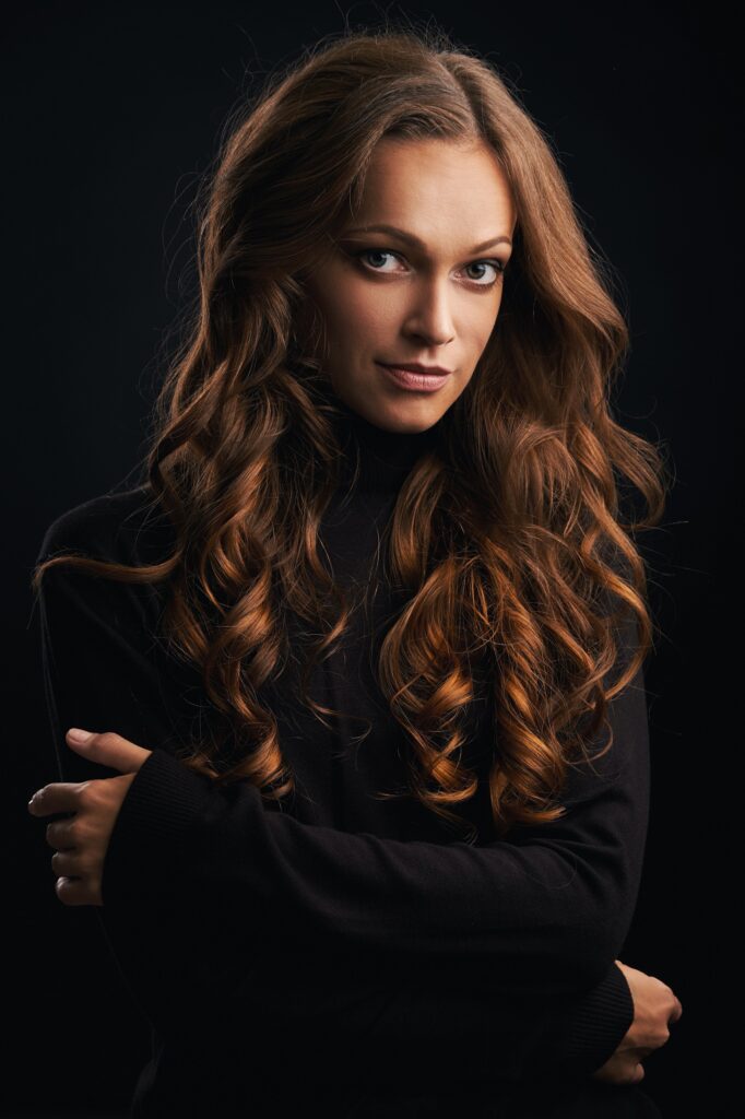 Brunette girl with long and shiny wavy hair. Beautiful model with curly hairstyle