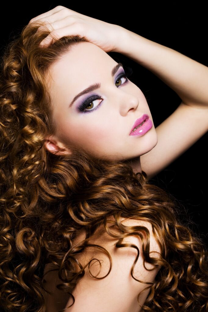 Bbeautiful  woman with beauty  long  hairs and bright pink make-up. On a black background